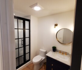 Modern bathroom electrical upgrade. Features the installation of a combination ceiling exhaust fan and LED light unit, a classic brushed-gold vanity wall sconce, and dedicated GFCI protected outlets for maximum code compliance and safety.