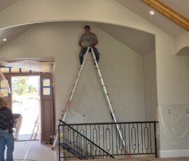 High-ceiling electrical installation in progress. Precision placement of recessed LED can lights across a vaulted tongue-and-groove ceiling, paired with a heavy-duty, large-profile modern ceiling fan installation.