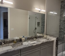 Luxury bathroom lighting and power integration. Features dual modern LED vanity light bars, clean hidden under-cabinet LED strip lighting for a soft ambient glow, and integrated ceiling ventilation fans.