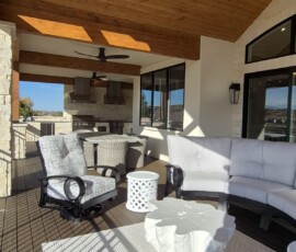 Outdoor living space electrical build-out. Weather-resistant, flush-mounted LED ceiling stone-puck lights installed seamlessly into a tongue-and-groove patio ceiling, alongside dual exterior ceiling fans and dedicated circuits for an outdoor kitchen/grill station.