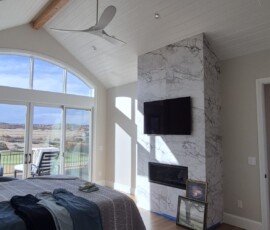 Bedroom suite electrical package. Installation of an extra-large modern ceiling fan mounted on a structural timber beam, dimmable recessed ambient lighting, and high-voltage wiring for a flush-mounted fireplace and entertainment center setup.