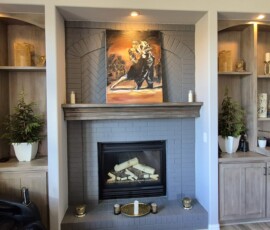 Integrated accent lighting and media wiring. Includes recessed alcove spotlighting to showcase custom shelving and artwork, paired with concealed wire routing for a seamless wall-mounted TV installation above the fireplace.